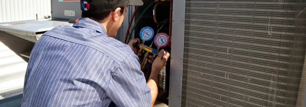 HVAC technician servicing a condenser unit in Wilton